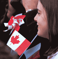 a member of the public, with a miniature Canada flag, and behind a windmill in Canada colours 